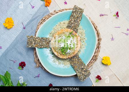 Ein blauer Tisch mit Speisen auf Tellern und ein floraler Herzstück auf blauem Stoff Stockfoto