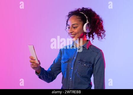 Junge Frau mit Kopfhörern über Smartphone Stockfoto