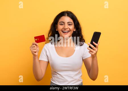 Fröhliche Frau mit Telefon und Kreditkarte Stockfoto
