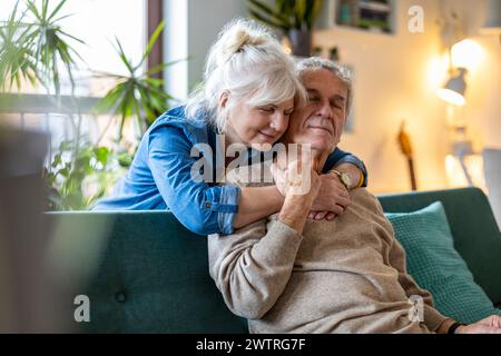 Porträt eines glücklichen Seniorenpaares, das zu Hause auf dem Sofa sitzt Stockfoto