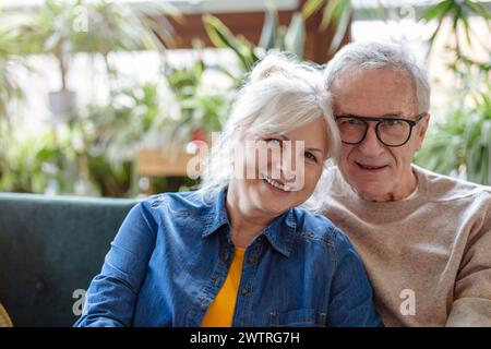 Porträt eines glücklichen Seniorenpaares, das zu Hause auf dem Sofa sitzt Stockfoto
