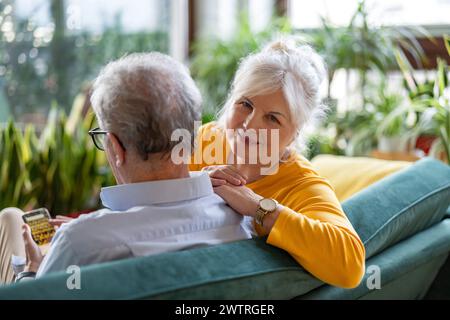 Porträt eines glücklichen Seniorenpaares, das zu Hause auf dem Sofa sitzt Stockfoto