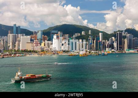 HONGKONG - 3. Juni 2015: Luftaufnahme eines Containerschiffs vor der Skyline des Victoria Harbour von Hongkong, 3. Juni 2015, Hongkong, China. Stockfoto