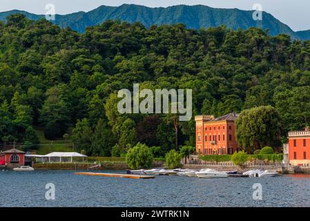 Comer See mit farbenfroher Villa im Wald und Booten in Lenno Comune, Lombardei, Italien. Italienische Landschaft. Beliebtes Reise- und Touristenziel auf Stockfoto