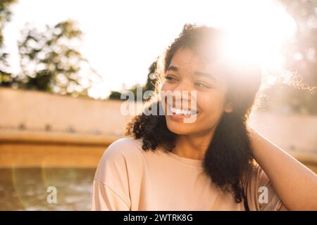 Nahporträt eines jungen lächelnden Teenagermädchens gemischter Rasse. Eine junge charmante Afroamerikanerin in einem beigen T-Shirt lacht draußen. A su Stockfoto