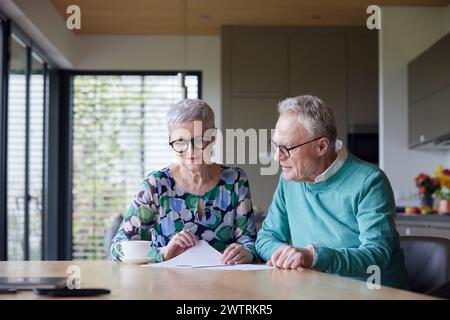 Seniorenpaar, das zu Hause am Tisch sitzt und das Dokument prüft Stockfoto