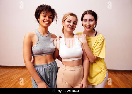 Multiethnische niedliche Freunde in Sportkleidung lächeln im Fitnessclub an. Attraktive Teenager-Mädchen verschiedener Rassen nach einem Workout im Fitnessstudio. Th Stockfoto