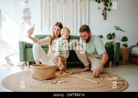 Mutter macht Selfie mit ihrer Familie im Wohnzimmer zu Hause Stockfoto