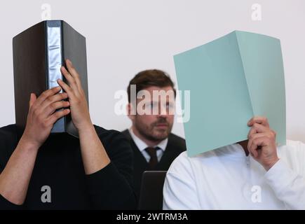 Augsburg, Deutschland. März 2024. Der Hauptangeklagte (r) sitzt im Dock eines Gerichtssaals neben anderen Angeklagten vor dem Anwalt Harald Stehr (M). Er wird angeklagt, dass er einen Sprengstoff explodieren lässt und schwere körperliche Schäden verursacht. Am 11. November 2023 soll der Mann während des Bundesliga-Spiels zwischen dem FC Augsburg und der TSG 1899 Hoffenheim einen Feuerwerkskörper im Besucherblock ausgelöst haben, was in Deutschland nicht erlaubt ist. Quelle: Karl-Josef Hildenbrand/dpa/Alamy Live News Stockfoto