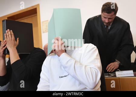 Augsburg, Deutschland. März 2024. Der Hauptangeklagte (M) sitzt neben anderen Angeklagten vor dem Anwalt Harald Stehr (r) im Dock eines Gerichtssaals. Er wird angeklagt, dass er einen Sprengstoff explodieren lässt und schwere körperliche Schäden verursacht. Der Mann soll am 11. November 2023 während des Bundesliga-Spiels zwischen dem FC Augsburg und der TSG 1899 Hoffenheim im Besucherblock einen Feuerwerkskörper in Gang gesetzt haben, der in Deutschland nicht erlaubt ist. Quelle: Karl-Josef Hildenbrand/dpa/Alamy Live News Stockfoto