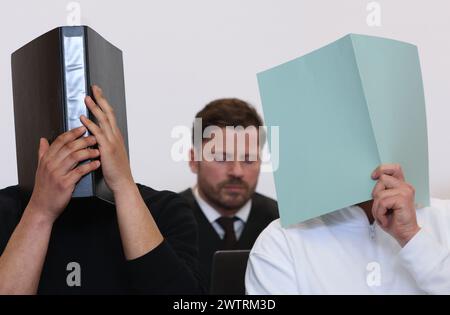 Augsburg, Deutschland. März 2024. Der Hauptangeklagte (r) sitzt im Dock eines Gerichtssaals neben anderen Angeklagten vor dem Anwalt Harald Stehr (M). Er wird angeklagt, dass er einen Sprengstoff explodieren lässt und schwere körperliche Schäden verursacht. Am 11. November 2023 soll der Mann während des Bundesliga-Spiels zwischen dem FC Augsburg und der TSG 1899 Hoffenheim einen Feuerwerkskörper im Besucherblock ausgelöst haben, was in Deutschland nicht erlaubt ist. Quelle: Karl-Josef Hildenbrand/dpa/Alamy Live News Stockfoto