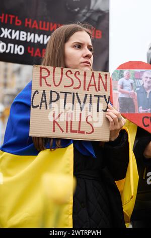 Patriotische ukrainische Frau mit Nationalflagge hält bei einer öffentlichen Demonstration das Banner "russische Gefangenschaft tötet". Kiew - 16. März 2024 Stockfoto