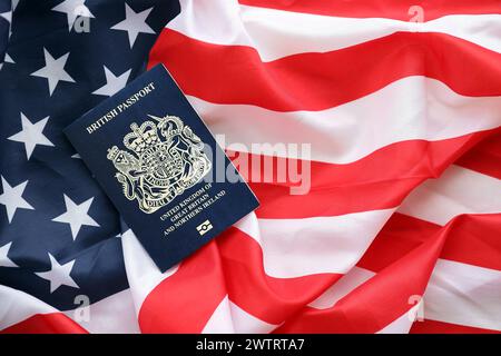 Blauer britischer Pass auf dem Hintergrund der US-Nationalflagge aus nächster Nähe. Tourismus und Diplomatie Stockfoto