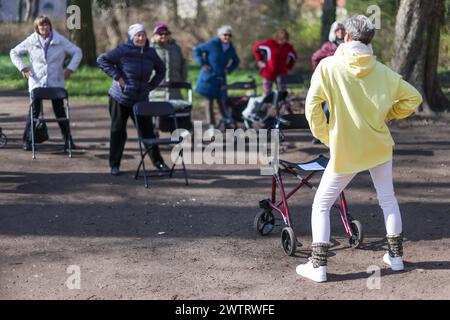 PRODUKTION - 13. März 2024, Sachsen-Anhalt, Köthen: Yogalehrerin Kathrin Fritzsche führt im Schlosspark Köthen einen Rollator-Yoga-Kurs für Senioren durch. Der Kurs bietet spezifische Übungen, die auf und außerhalb des Rollators durchgeführt werden können. Foto: Jan Woitas/dpa Stockfoto