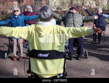 PRODUKTION - 13. März 2024, Sachsen-Anhalt, Köthen: Yogalehrerin Kathrin Fritzsche führt im Schlosspark Köthen einen Rollator-Yoga-Kurs für Senioren durch. Der Kurs bietet spezifische Übungen, die auf und außerhalb des Rollators durchgeführt werden können. Foto: Jan Woitas/dpa Stockfoto