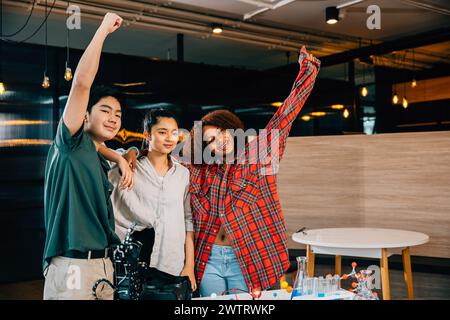 Energiegeladene Schüler heben die Hände, um ein erfolgreiches Engagement in der Robotik zu feiern Stockfoto