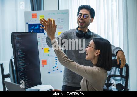 asiatische und indische Entwicklerteams klatschen Hand für Projekterfolg mit Software-Computer im Büro Stockfoto