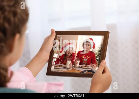 Kleines Mädchen mit Rahmen mit Foto-Porträt ihrer Familie drinnen, Nahaufnahme Stockfoto