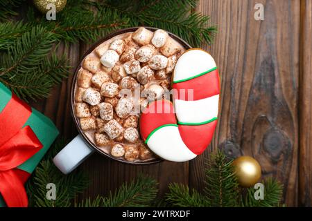 Leckerer Weihnachtskeks in Form von Zuckerrohr, Dekor und Kakao mit Marshmallows auf Holztisch, flach gelegen. Leerzeichen für Text Stockfoto