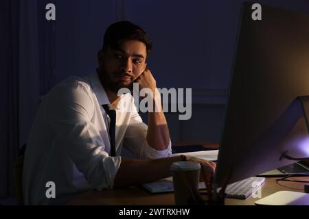 Müder junger Mann, der spät im Amt arbeitet Stockfoto