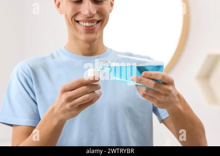 Junger Mann, der Mundwasser im Bad benutzt, Nahaufnahme Stockfoto