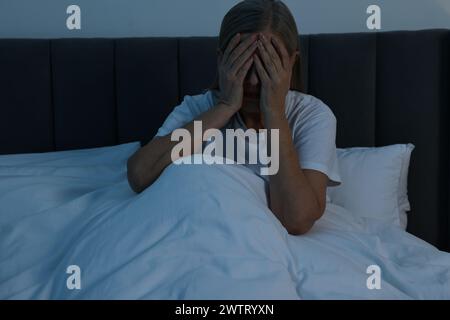 Frau, die nachts im Bett Kopfschmerzen hat Stockfoto