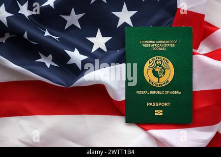 Grüner nigerianischer Pass auf dem Hintergrund der US-Nationalflagge aus nächster Nähe. Tourismus und Diplomatie Stockfoto