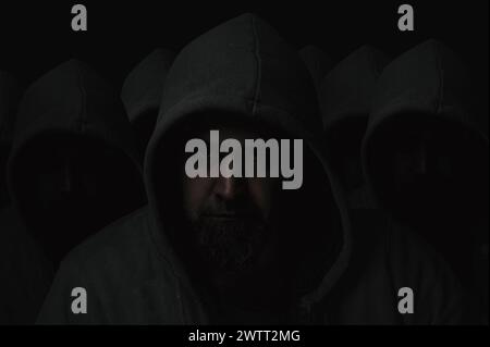 Silhouetten mysteriöser Männer mit dunklem Gesicht und nicht sichtbarem Gesicht, die Kapuzenpullover auf dunklem Hintergrund tragen Stockfoto