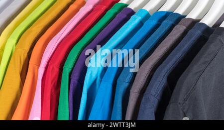 Bunte T-Shirts hängen auf einem Regal, Hintergrund Stockfoto