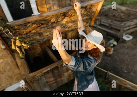 Outdoor-Enthusiasten aus Denim lächeln, wenn sie ein Ei im Hühnernest finden Stockfoto