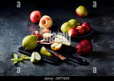 Eine Auswahl an frischen, geschnittenen Früchten, die kunstvoll auf einer dunklen, strukturierten Oberfläche angeordnet sind. Stockfoto