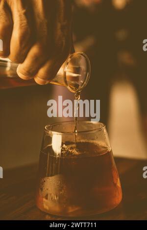 Eine Person, die Espresso in ein Glas auf einem Tisch gießt Stockfoto