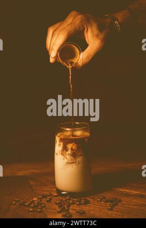 Eine Hand, die Espresso und Eis in ein Glas gießt Stockfoto