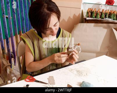 Ein Künstler bastelt sorgfältig eine kleine Skulptur in einer bunten Werkstatt. Stockfoto