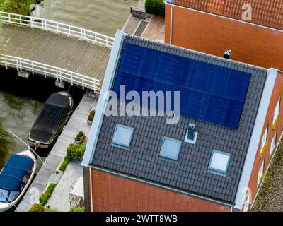 Blick aus der Vogelperspektive auf das Wohngebiet mit Kanal, Boot und Solarpaneelen auf dem Dach. Stockfoto