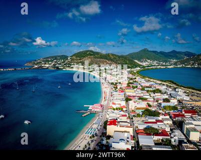 Aus der Vogelperspektive auf eine lebhafte Küstenstadt mit üppigen grünen Hügeln und klarem blauem Wasser. Stockfoto
