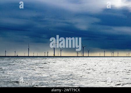 Windturbinen dominieren den Horizont über einem stürmischen Meer unter einem stimmungsvollen Himmel Stockfoto