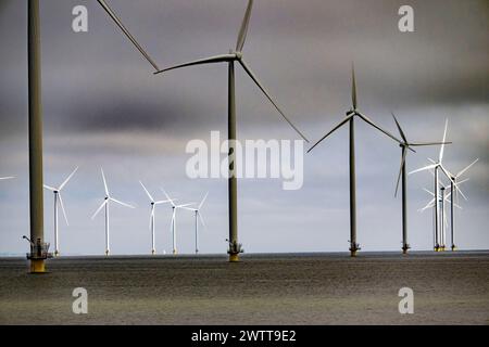 Windturbinen stehen hoch über dem Meer unter bewölktem Himmel. Stockfoto