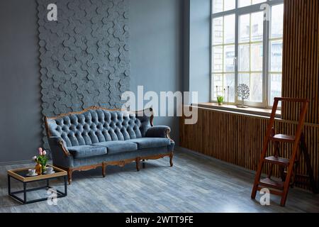 Moderne Einrichtung mit dunklem klassischem Luxussofa, Couchtisch, großem Fenster und grauer strukturierter Wand. Stilvolles Wohnzimmer Stockfoto