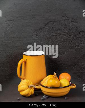 Ein gemütliches herbstliches Stillleben mit einem Becher in warmen Tönen und einer Schüssel mit Kürbissen und Orangen Stockfoto