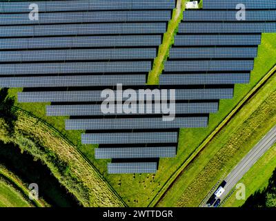Luftaufnahme eines Solarparks, der eine Straße mit fahrenden Autos flankiert Stockfoto