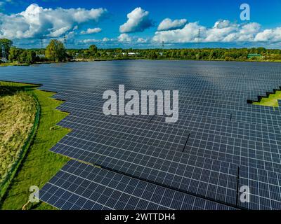 Riesiger Solarpark, der sich über die Landschaft unter einem teilweise bewölkten Himmel erstreckt Stockfoto