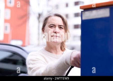 Frau, die ihr Elektroauto auflädt Stockfoto