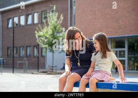 Ein herzerwärmender Moment, in dem Mutter und ihre kleine Tochter einen sonnigen Tag miteinander verbringen, Lächeln und Gespräche austauschen. Stockfoto