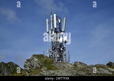 Metallturm mit verschiedenen Telekommunikationsantennen auf einem Berg, vor blauem Himmel, im Frühjahr. Sicherstellung des Betriebs von Stockfoto