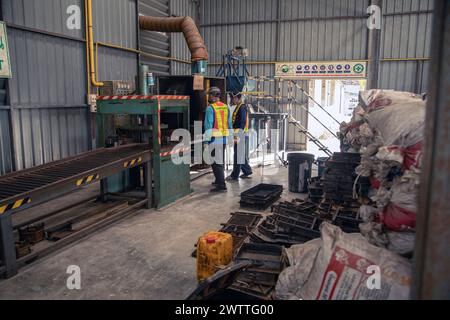 Arbeiter, die Maschinen in einer Kunststoffrecyclingfabrik in Thailand überwachen Stockfoto