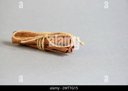 Zimtstangen mit Garn auf grauem Hintergrund gebunden. Natürliches Licht. Seitenansicht. Selektiver Fokus. Kopierbereich. Stockfoto