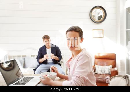 Frau mit Laptop und Mann, der zu Hause Kaffee trinkt Stockfoto