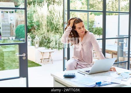 Frau, die an einem Laptop in einem hellen Home Office arbeitet. Stockfoto