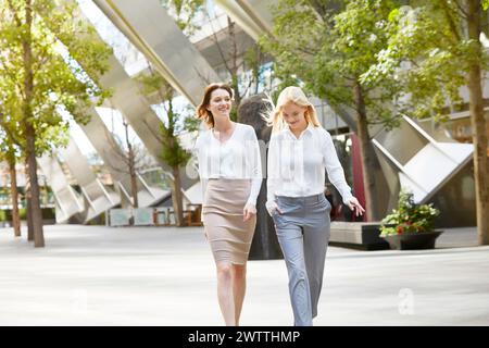 Zwei Frauen, die auf einem städtischen platz spazieren gehen und plaudern Stockfoto